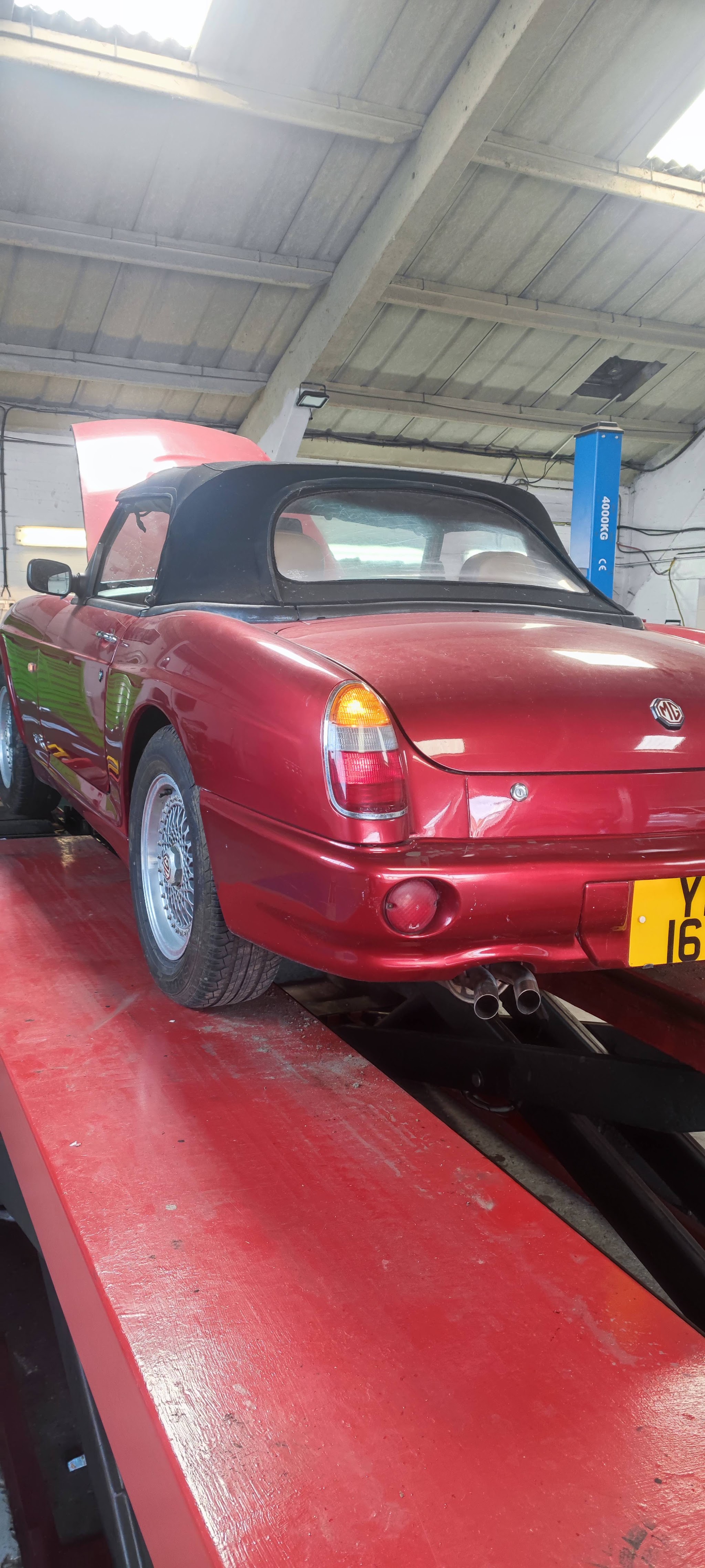 Red MG convertible on the ramp in the workshop