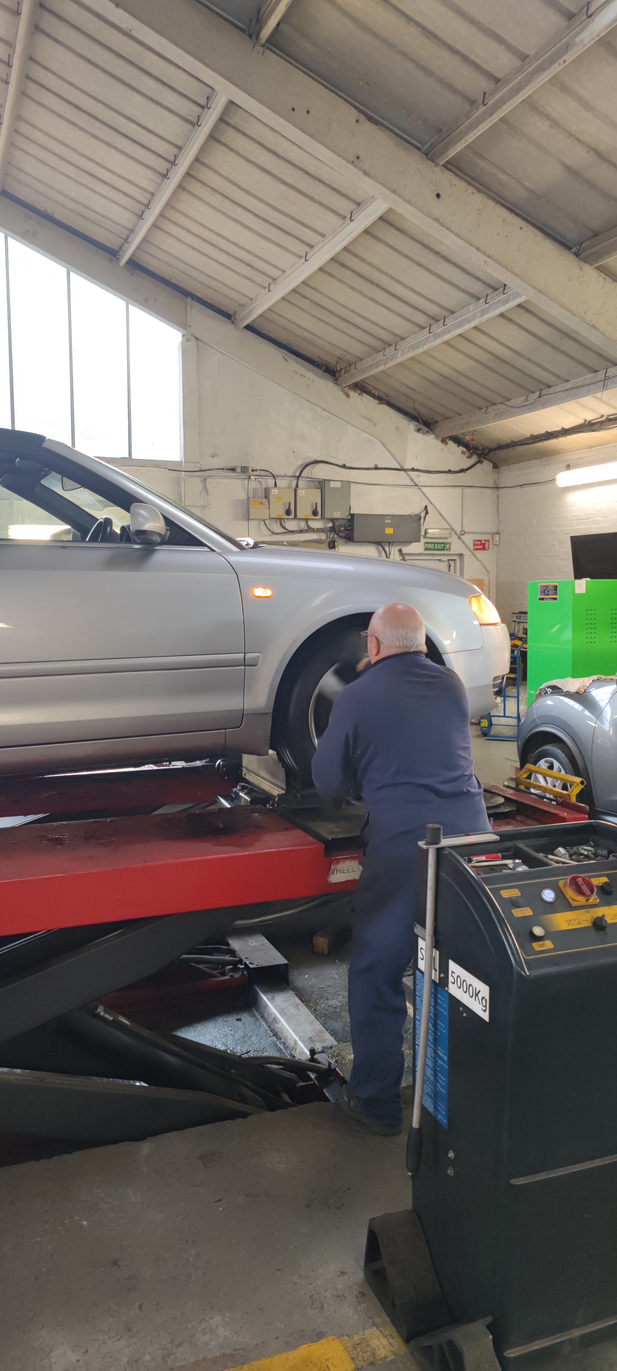 Mechanic at a silver car on the workshop ramp