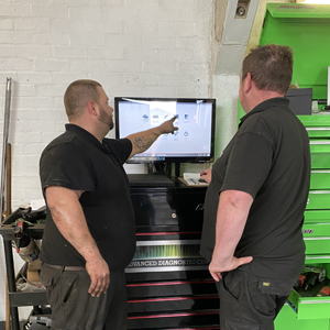 Two mechanics reviewing results on a workshop screen