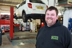 Smiling KCS team member beside a raised car