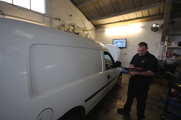 Technician checking a white van in the workshop bay